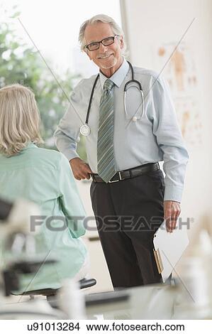 Picture - Male doctor talking to female patient in his office. Fotosearch