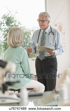 Stock Photo - Male doctor talking to female patient in his office. Fotosearch