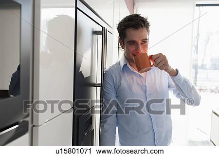 Stock Image - Man drinking coffee in kitchen. Fotosearch