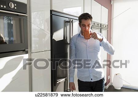Man drinking coffee in kitchen View Large Photo Image Stock Photo - Man drinking coffee in kitchen. Fotosearch