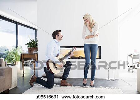 Stock Image - Man playing guitar in front of woman. Fotosearch