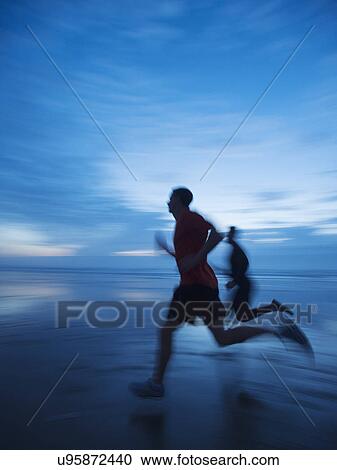 Stock Image - Man running along beach. Fotosearch