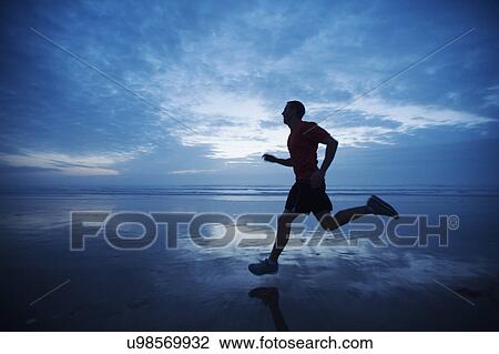 Stock Image - Man running along beach. Fotosearch