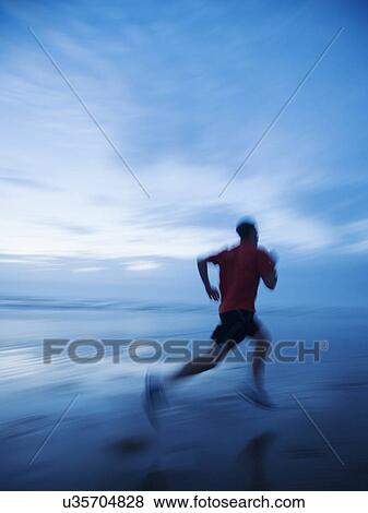 Stock Photo - Man running along beach. Fotosearch