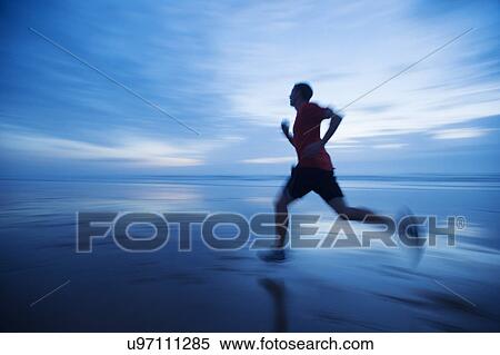 Stock Photography - Man running along beach. Fotosearch