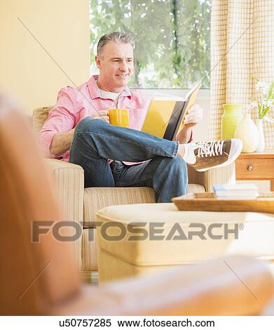 Man sitting on sofa and reading book View Large Photo Image Stock Photography - Man sitting on sofa and reading book. Fotosearch