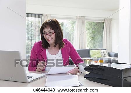 Stock Image - Mature businesswoman doing paperwork. Fotosearch