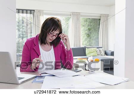 Stock Image - Mature businesswoman doing paperwork. Fotosearch