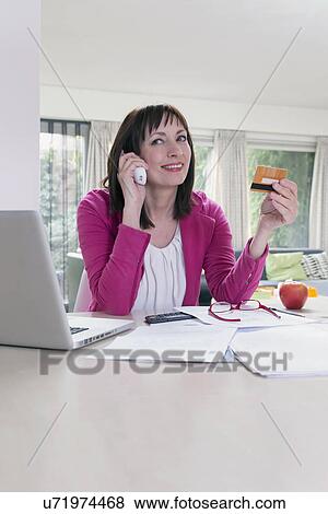 Mature businesswoman talking on phone and using credit card View Large Photo Image Stock Photo - Mature businesswoman talking on phone and using credit card. Fotosearch