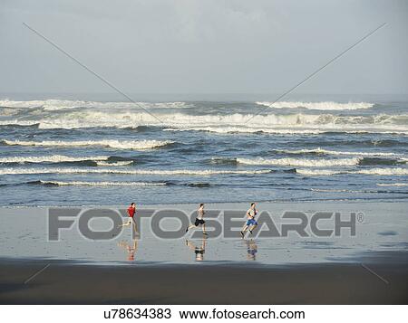 Stock Image - Men running on beach. Fotosearch
