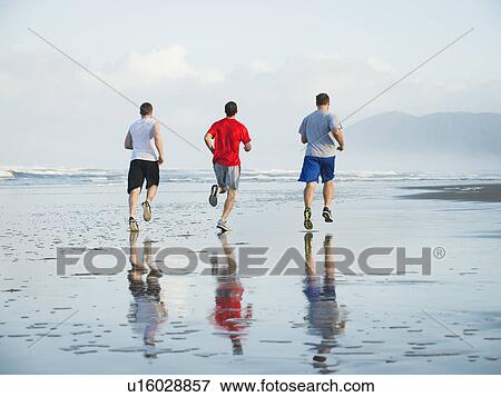 Stock Photo - Men running on beach. Fotosearch