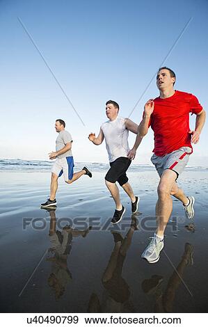 Stock Photo - Men running on beach. Fotosearch