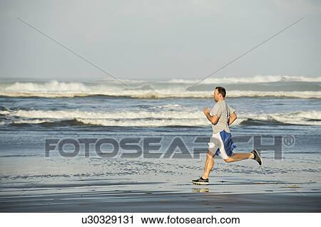 Mid adult man running on beach View Large Photo Image Stock Image - Mid adult man running on beach. Fotosearch