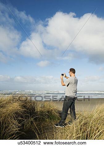 Stock Image - Mid adult man taking photograph. Fotosearch