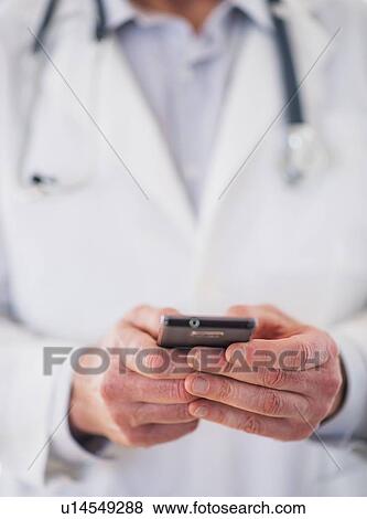 Stock Photo - Mid section of doctor using mobile phone. Fotosearch