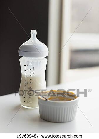 Stock Photo - Milk in baby bottle and small bowl on table. Fotosearch