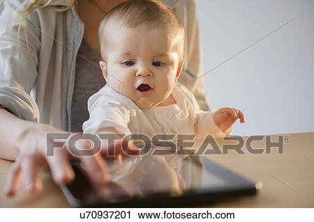 Mother and baby daughter (6-11 months) playing with digital tablet View Large Photo Image Stock Image - Mother and baby daughter (6-11 months) playing with digital tablet. Fotosearch