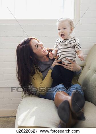Mother and daughter (12-17 months) playing on sofa, Laughing and having fun View Large Photo Image Stock Photo - Mother and daughter (12-17 months) playing on sofa, Laughing and having fun. Fotosearch