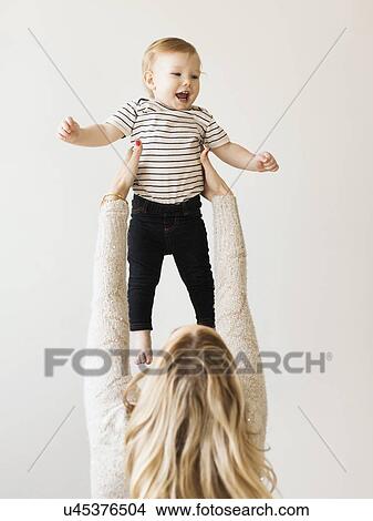 Picture - Mother holding up her daughter (12-17 months) . Fotosearch