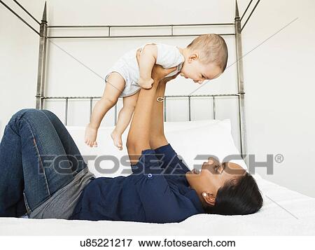 Stock Photo - Mother lifting her son (2-5 month), playing happily. Fotosearch