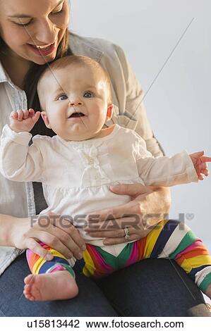 Stock Image - Mother playing with baby daughter (6-11 months). Fotosearch