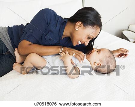 Stock Photograph - Mother playing with her son (2-5 months). Fotosearch
