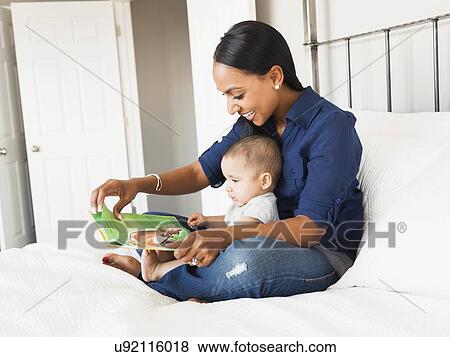 Stock Photo - Mother showing her son (2-5 months) book and reading. Fotosearch