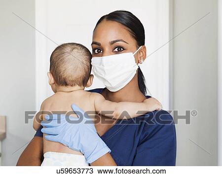 Stock Image - Nurse holding in arms baby boy (2-5 months). Fotosearch