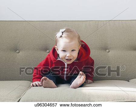 Portrait of baby girl (12-17 months) sitting on sofa View Large Photo Image Stock Photo - Portrait of baby girl (12-17 months) sitting on sofa. Fotosearch