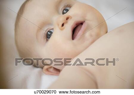 Stock Image - Portrait of baby girl (6-11 months) lying down. Fotosearch
