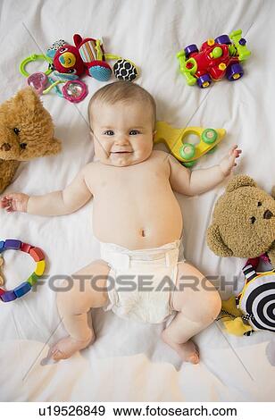 Portrait of baby girl (6-11 months) lying down among toys View Large Photo Image Stock Photo - Portrait of baby girl (6-11 months) lying down among toys. Fotosearch