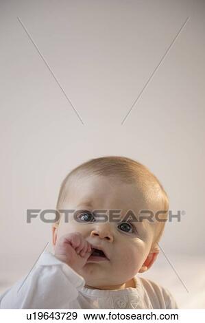 Stock Photo - Portrait of baby girl (6-11 months) sitting in bed with stack of books. Fotosearch
