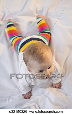 Portrait of baby girl (6-11 months) lying on bed View Large Photo Image Stock Photograph - Portrait of baby girl (6-11 months) lying on bed. Fotosearch