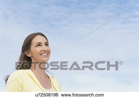 Stock Photograph - Portrait of beautiful young woman against sky. Fotosearch