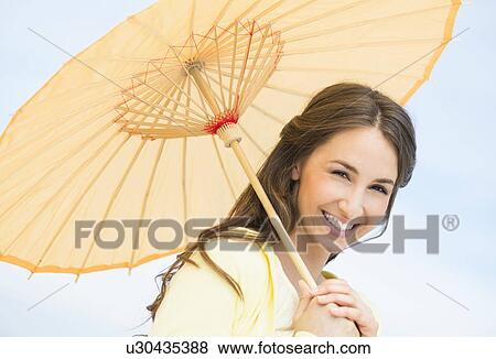 Stock Photo - Portrait of beautiful young woman with parasol. Fotosearch