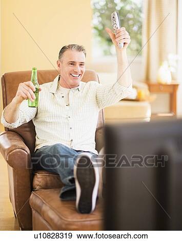 Portrait of cheerful man watching tv View Large Photo Image Stock Photo - Portrait of cheerful man watching tv. Fotosearch