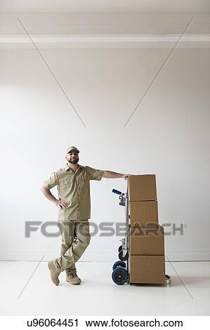 Portrait of delivery man standing next to push cart View Large Photo Image Stock Image - Portrait of delivery man standing next to push cart. Fotosearch