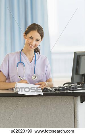Stock Photo - Portrait of female nurse at nurse's station in hospital. Fotosearch