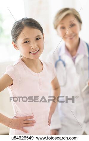 Portrait of girl (8-9) and doctor in background View Large Photo Image Stock Photo - Portrait of girl (8-9) and doctor in background. Fotosearch