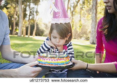 Stock Image - Portrait of happy family in park celebrating daughter's (4-5 years) birthday. Fotosearch
