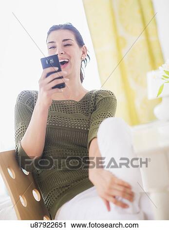 Stock Image - Portrait of happy woman using mobile phone. Fotosearch