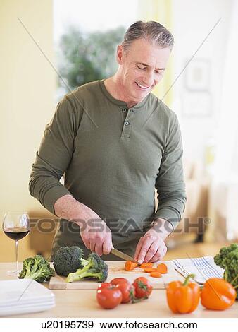 Stock Photo - Portrait of man cutting vegetables. Fotosearch