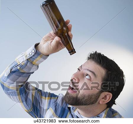 Portrait of man holding empty beer bottle and looking into it View Large Photo Image Stock Image - Portrait of man holding empty beer bottle and looking into it. Fotosearch