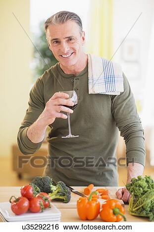 Portrait of man in kitchen, holding wine glass View Large Photo Image Stock Photograph - Portrait of man in kitchen, holding wine glass. Fotosearch