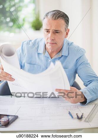 Picture - Portrait of man looking at blueprints in office. Fotosearch