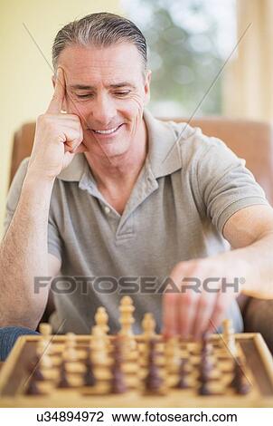 Stock Image - Portrait of man playing chess. Fotosearch