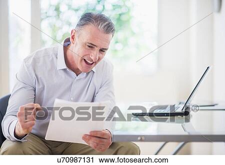 Portrait of man reading documents in office View Large Photo Image Stock Image - Portrait of man reading documents in office. Fotosearch