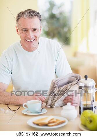 Portrait of man reading newspaper and having breakfast View Large Photo Image Stock Image - Portrait of man reading newspaper and having breakfast. Fotosearch
