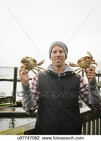 Stock Image - Portrait of man showing crabs. Fotosearch
