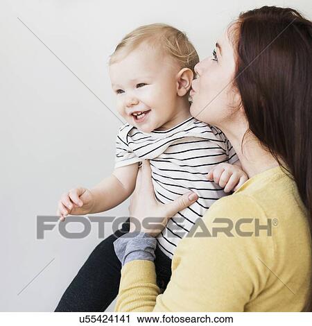 Portrait of mother kissing her daughter (12-17 months) View Large Photo Image Stock Image - Portrait of mother kissing her daughter (12-17 months). Fotosearch